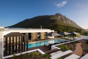 a building with a pool with a mountain in the background at Vyn Guest House Hout Bay in Hout Bay