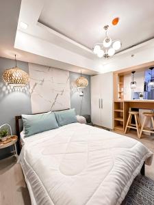 een slaapkamer met een groot wit bed en een keuken bij Azure North NextDoor Nest in Lagundi