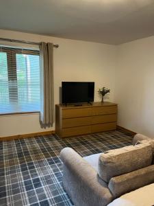 a living room with a flat screen tv and a couch at Tigh Stobban Apartment 1 in Fort William