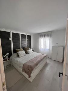 a white bedroom with a large bed and a window at Apartamento Casa Carmen Teguisol in Costa Teguise