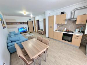 - un salon et une cuisine avec une table et un canapé bleu dans l'établissement Blue95, à Mamaia Nord – Năvodari
