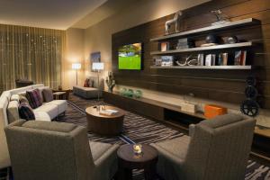 a living room with two chairs and a tv at Courtyard by Marriott Irvine Spectrum in Irvine