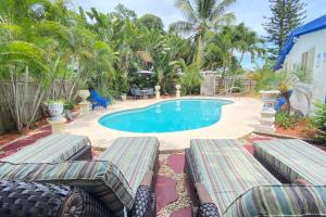 a swimming pool with chaise lounges in front of a house at Great location Pool home w Pool table 5br in Fort Lauderdale