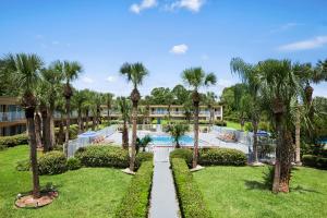 a resort with a swimming pool and palm trees at Days Inn by Wyndham Daytona Beach Speedway in Daytona Beach