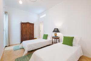two beds in a room with white walls and green pillows at Casa Largo da Mó in Portimão
