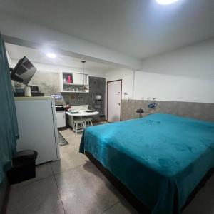 a bedroom with a blue bed and a kitchen at STUDIO 302 | WIFI 600MB | RESIDENCIAL JC, um lugar para ficar. in Carmo