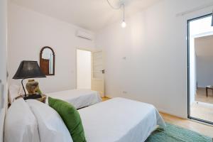 a white bedroom with two beds and a lamp at Casa Largo da Mó in Portimão