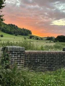 a brick wall in a field with a sunset in the background at Gorgeous Cottage in Skirmett with Parking in Henley on Thames