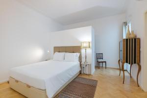 a bedroom with a large white bed and a chair at Casa Largo da Mó in Portimão