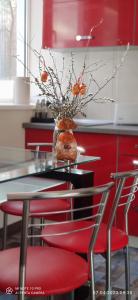 una mesa con sillas rojas y un jarrón con naranjas. en Varnukroga House, en Jūrmala