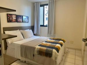 um quarto com uma cama grande e uma janela em Beira Mar Pajuçara com Varanda 203 - frente piscinas naturais e feira artesanato em Maceió