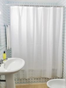 a bathroom with a white shower curtain and a sink at Garden's Nest - North Villa in Conceição