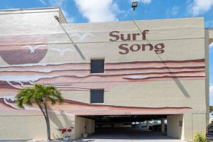 a surf song sign on the side of a building at 239 Surf Song Resort in St. Pete Beach
