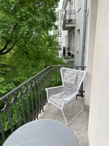 Un balcón con una silla blanca y una mesa. en Studio na Starej Ochocie, en Varsovia