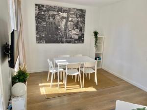 2 BDR EIXAMPLE APARTMENT في برشلونة: غرفة طعام مع طاولة بيضاء وكراسي