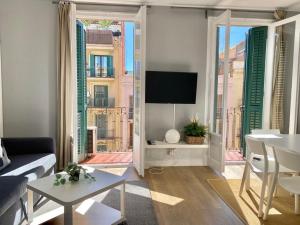2 BDR EIXAMPLE APARTMENT في برشلونة: غرفة معيشة بها أريكة وتلفزيون ونافذة
