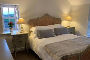 a bedroom with a large bed with two lamps on tables at Folly Farm Cottage, Cosy, Secluded near to St Ives in St Ives