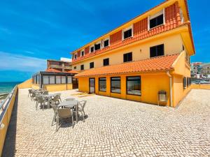 un edificio con mesas y sillas junto al océano en HI Areia Branca - Pousada de Juventude, en Areia Branca