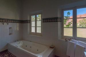 a white bath tub in a bathroom with windows at Hotel El Manantial del Silencio in Purmamarca +27 photos