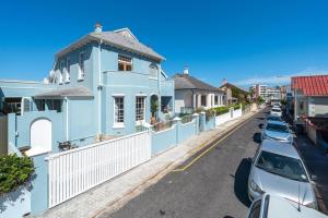 una casa blu su una strada con auto parcheggiate di 'Imagine' - Surfers Corner Muizenberg Village a Città del Capo