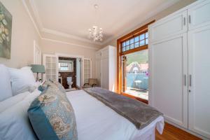 a bedroom with a white bed and a window at 'Imagine' - Surfers Corner Muizenberg Village in Cape Town