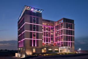 a tall building with pink lights on it at Aloft Muscat in Muscat