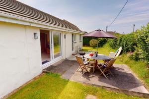 a patio with a table and chairs and an umbrella at CROYDE PEACH COTTAGE 3 Bedrooms in Croyde