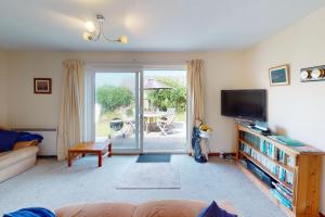 a living room with a couch and a tv at CROYDE PEACH COTTAGE 3 Bedrooms in Croyde