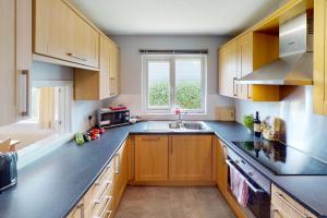 a kitchen with wooden cabinets and a sink and a window at CROYDE PEACH COTTAGE 3 Bedrooms in Croyde +17 photos