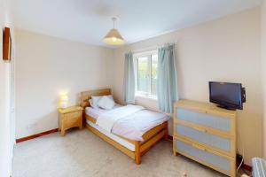 a small bedroom with a bed and a television at CROYDE PEACH COTTAGE 3 Bedrooms in Croyde