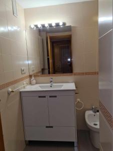 ein Badezimmer mit einem Waschbecken, einem Spiegel und einem WC in der Unterkunft Mediterrania Mar Canet in Canet d'en Berenguer