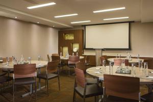 une salle de conférence avec des tables et des chaises et un écran de projection dans l'établissement AC Hotel Kansas City Plaza, à Kansas City