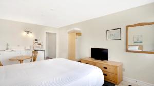 een slaapkamer met een wit bed en een keuken bij Homeport Motel in Lunenburg