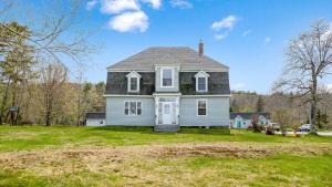 een wit huis met een zwart dak op een tuin bij Homeport Motel in Lunenburg