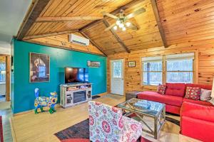 a living room with a red couch and a tv at High Peak Heaven Cozy Log Cabin on 1 Acre! in Windham