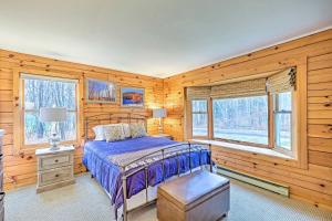 a bedroom with wooden walls and a bed and windows at High Peak Heaven Cozy Log Cabin on 1 Acre! in Windham