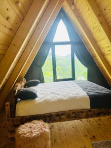 a bed in a room with a large window at sataplebungalov in Çamlıhemşin