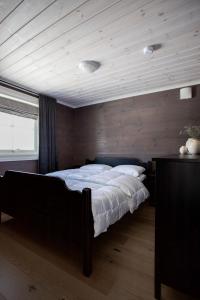 1 dormitorio con 1 cama grande y pared de madera en Penthouse apartment at Strandafjellet en Stranda