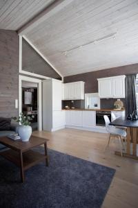 cocina y sala de estar con armarios blancos y mesa en Penthouse apartment at Strandafjellet en Stranda