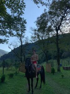 a young boy riding a horse in a field at nahei cottage in Martvili