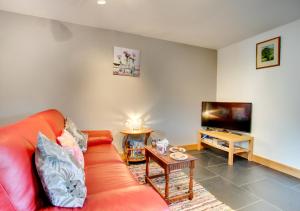 a living room with a red couch and a flat screen tv at Crud y Wennol in Llandderfel