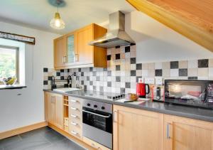 a kitchen with wooden cabinets and a stove top oven at Crud y Wennol in Llandderfel