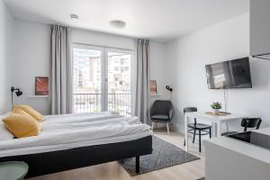 a white bedroom with a large bed and a desk at Hiisi Homes Turku Fleminginkatu in Turku