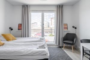 a bedroom with two beds and a chair and a window at Hiisi Homes Turku Fleminginkatu in Turku