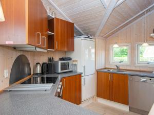 cocina con armarios de madera y nevera blanca en 6 person holiday home in Hemmet, en Falen