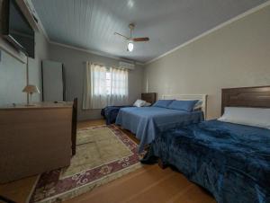1 dormitorio con 2 camas y ventilador de techo en Pousada Boschetti, en Gramado