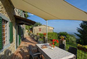 Petrognano的住宿－Casa Serena，阳台配有桌椅和遮阳伞