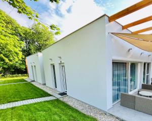 a white house with a green yard at Aranygesztenye Apartmanház in Balatonudvari