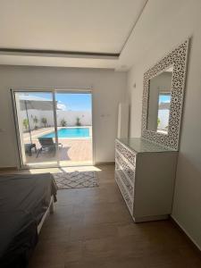 1 dormitorio con espejo y vistas a la piscina en Magnifique Villa moderne piscine SANS VIS À VIS DJERBA Midoun, en Taguermess