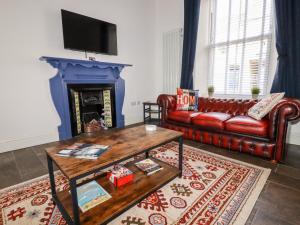 a living room with a red leather couch and a fireplace at Meneage House in Helston